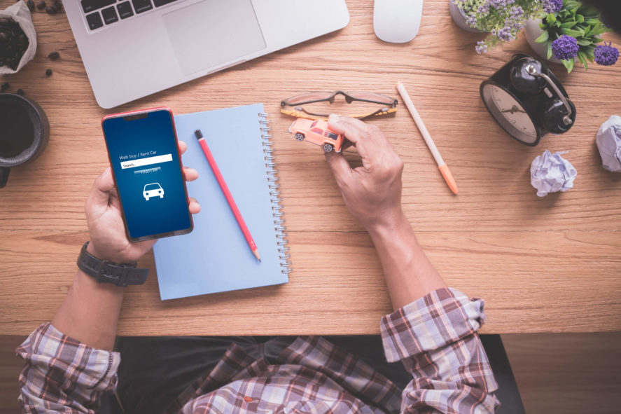 used-car-research-man-on-iphone-at-desk