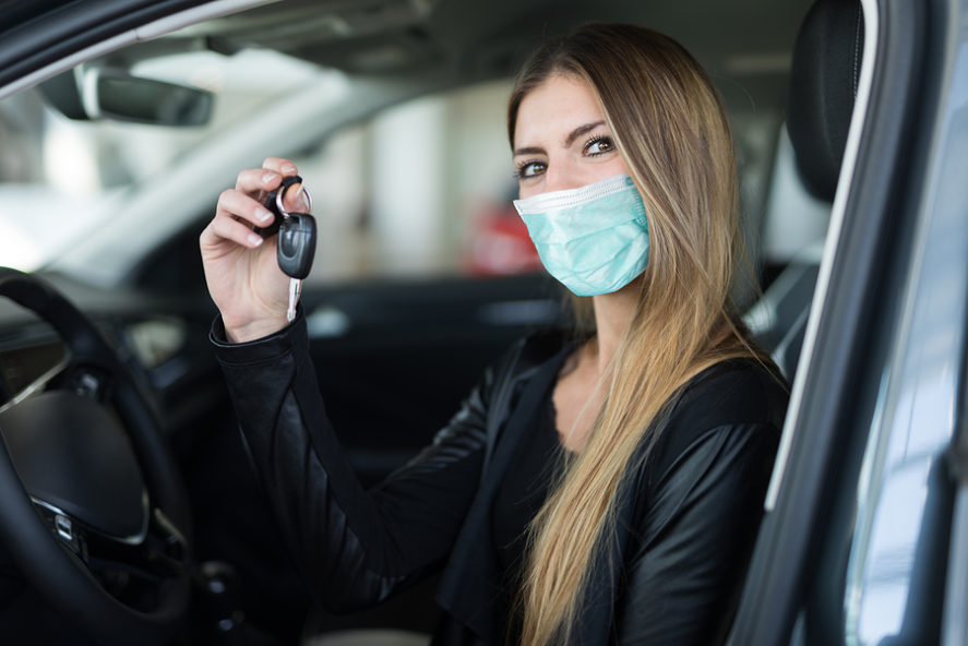 Masked-woman-showing-the-key-to-her-new-used-car