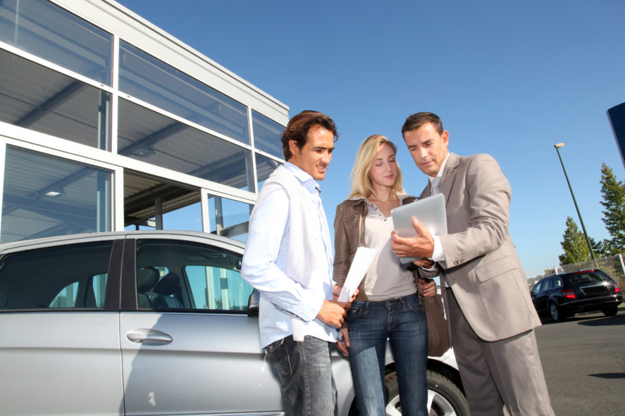 Car-Seller-With-Couple-Looking-At-Tablet-scaled